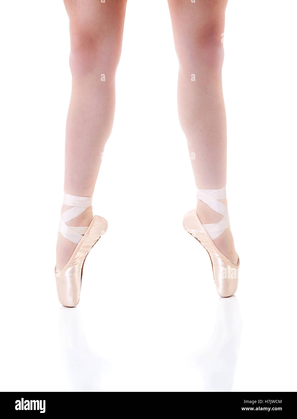 Focus on young ballerina's legs wearing pointe shoes with reflections. Isolated on white with copy space. Stock Photo
