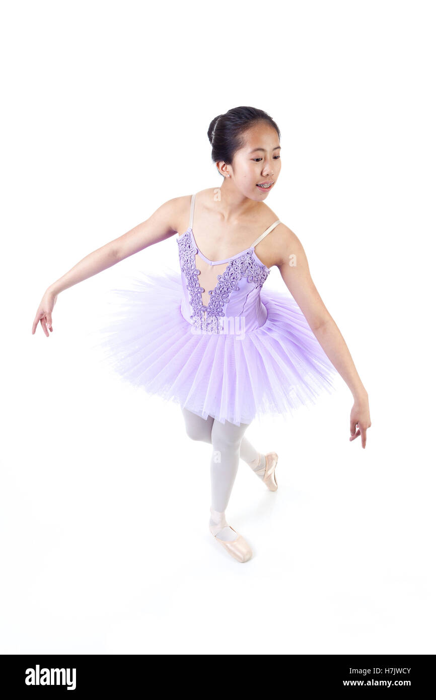 Young Asian ballerina with braces wearing purple tutu and pointe shoes dancing. Isolated on white background. Stock Photo