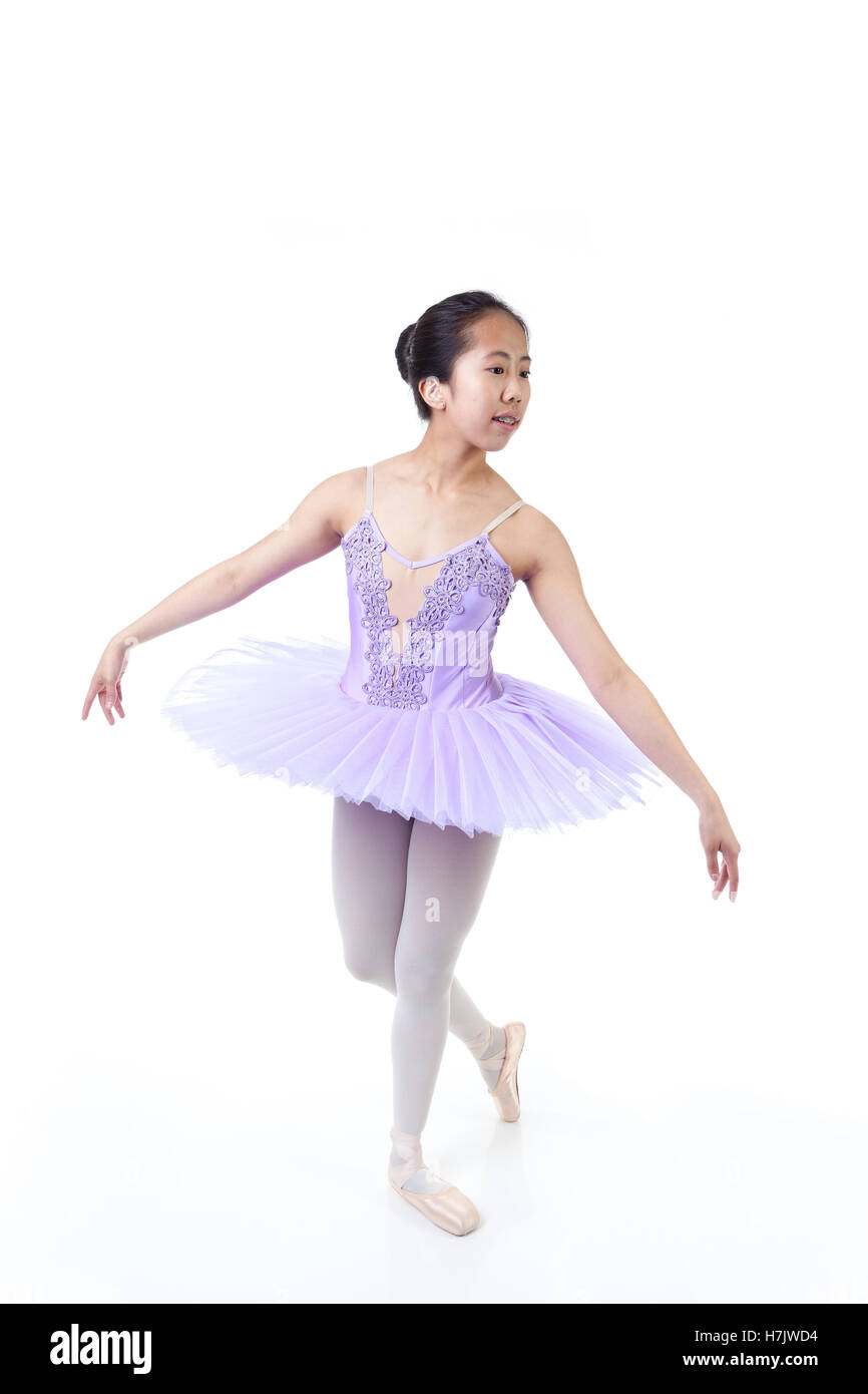 Young Asian ballerina with braces wearing purple tutu and pointe shoes dancing. Isolated on white background. Stock Photo