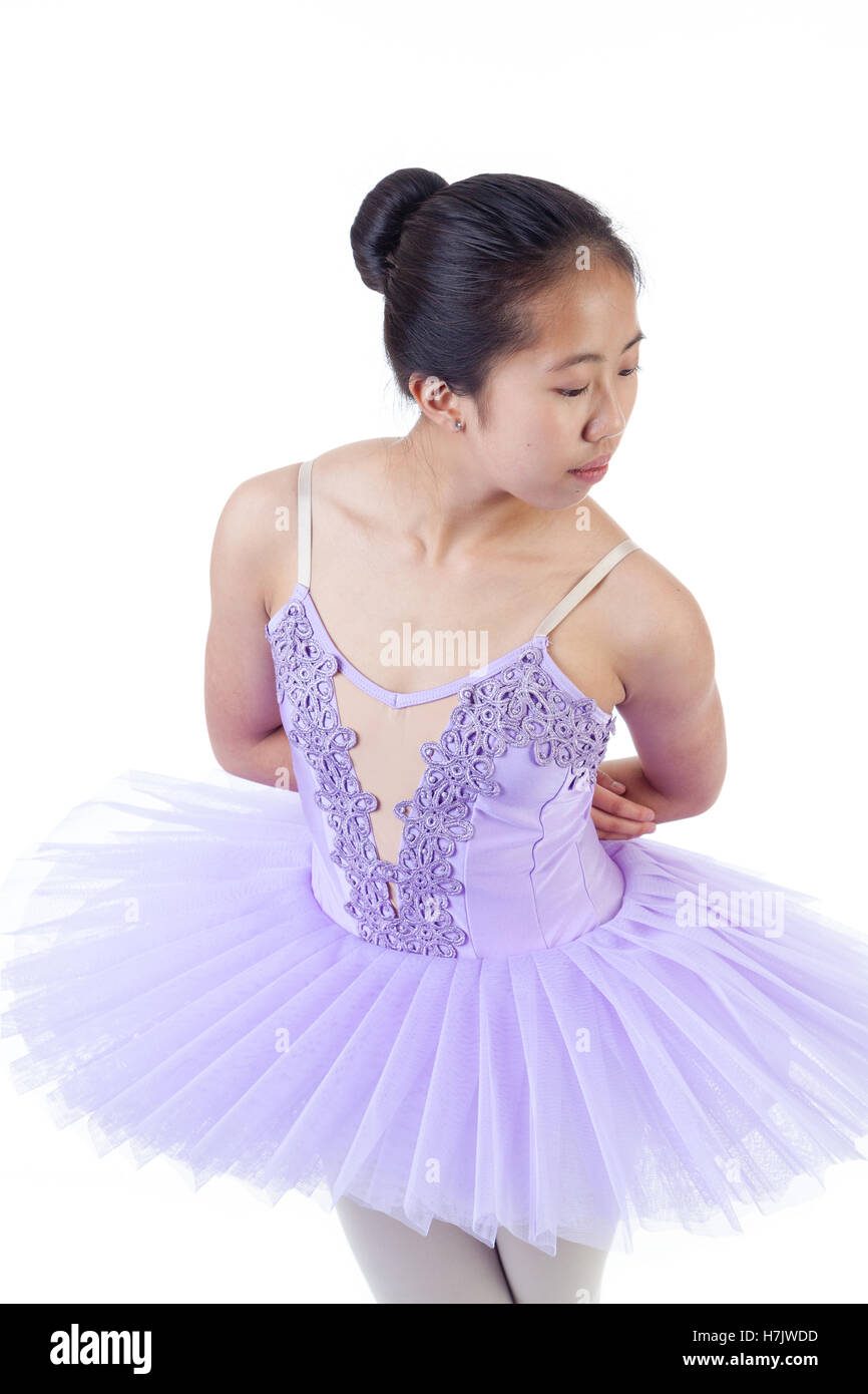 Young Asian ballerina wearing purple tutu and pointe shoes dancing. Isolated on white background. Stock Photo