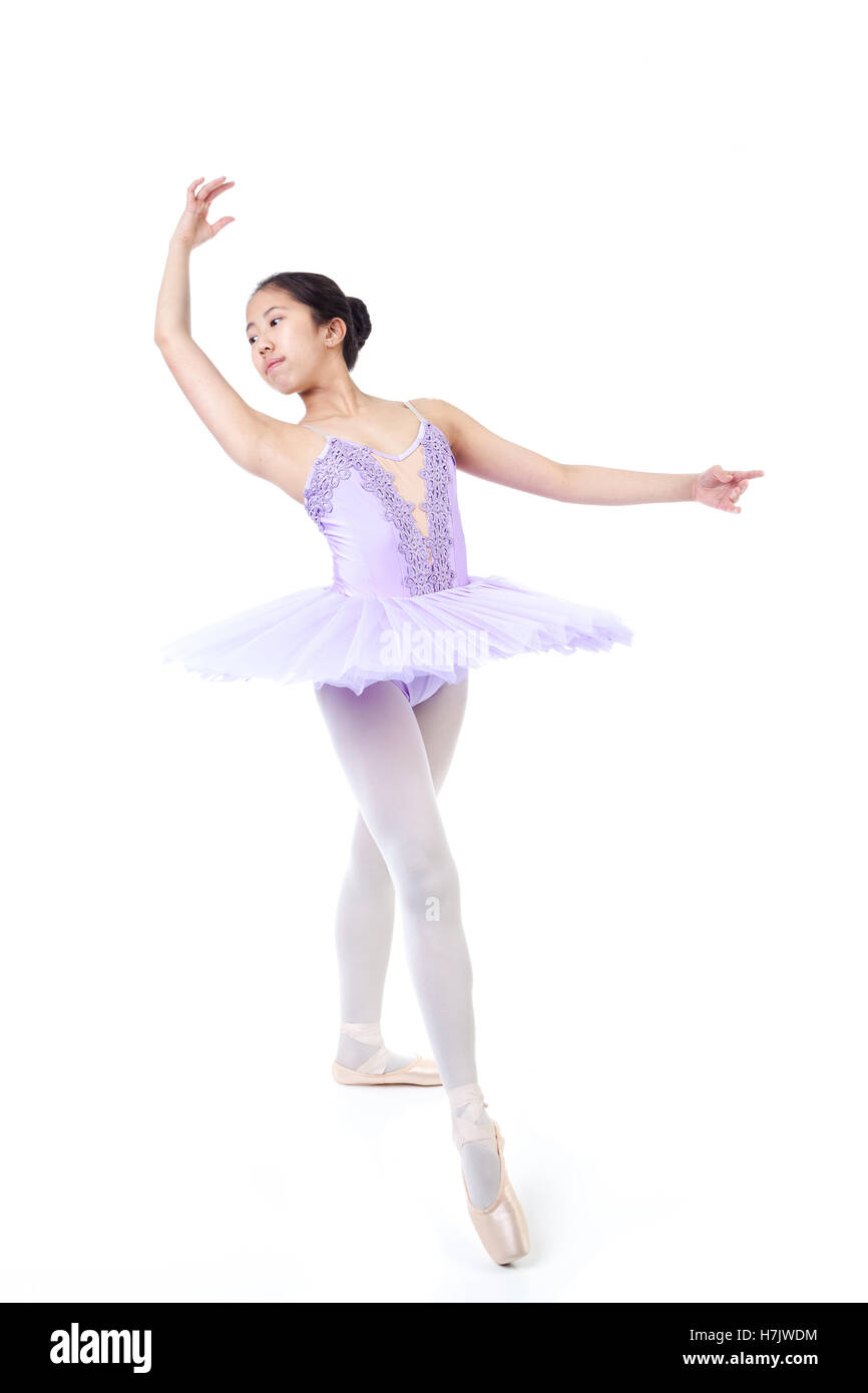 Young Asian ballerina wearing purple tutu and pointe shoes dancing. Isolated on white background. Stock Photo