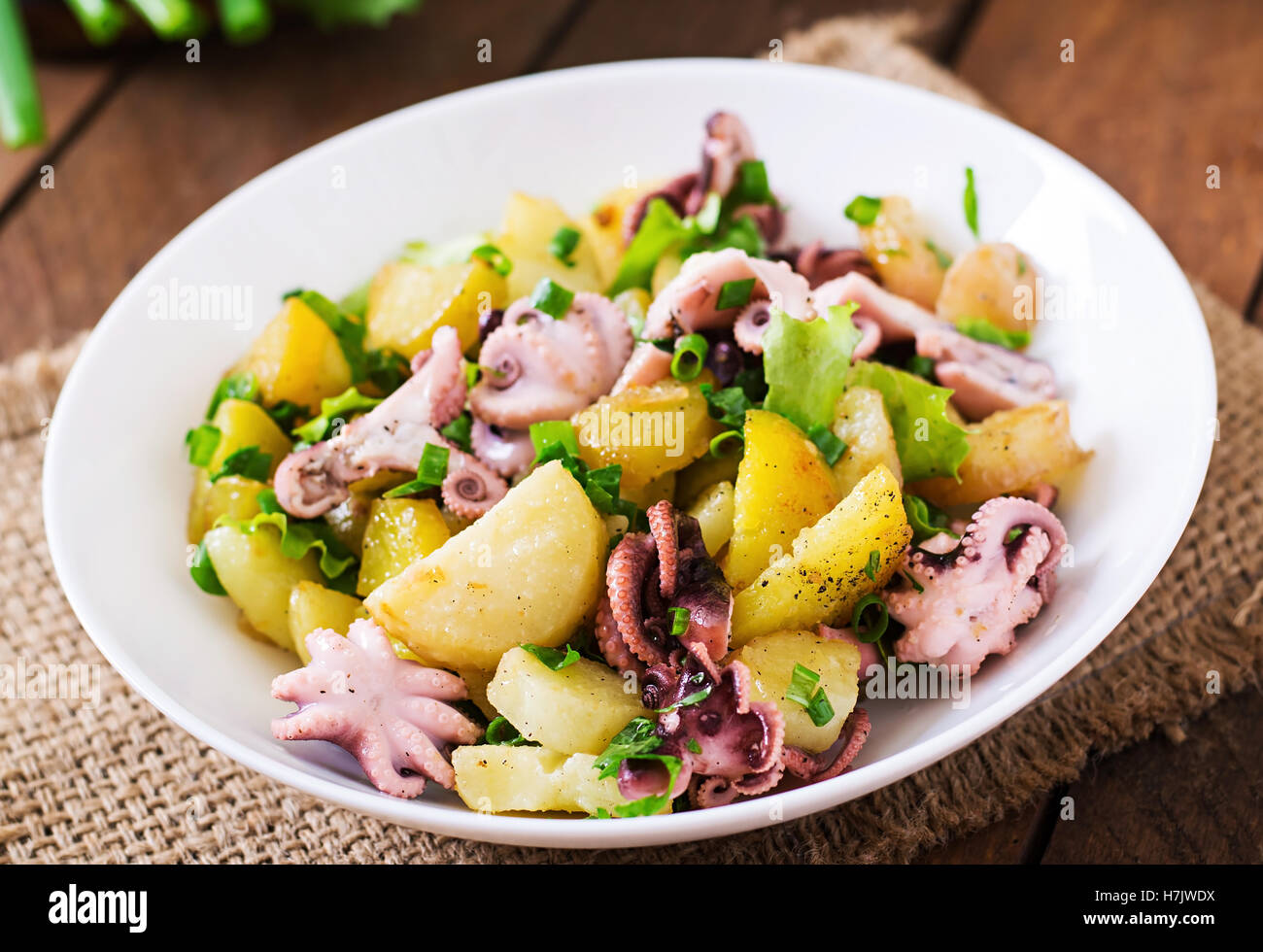 Potato salad with pickled octopus and green onions. Stock Photo