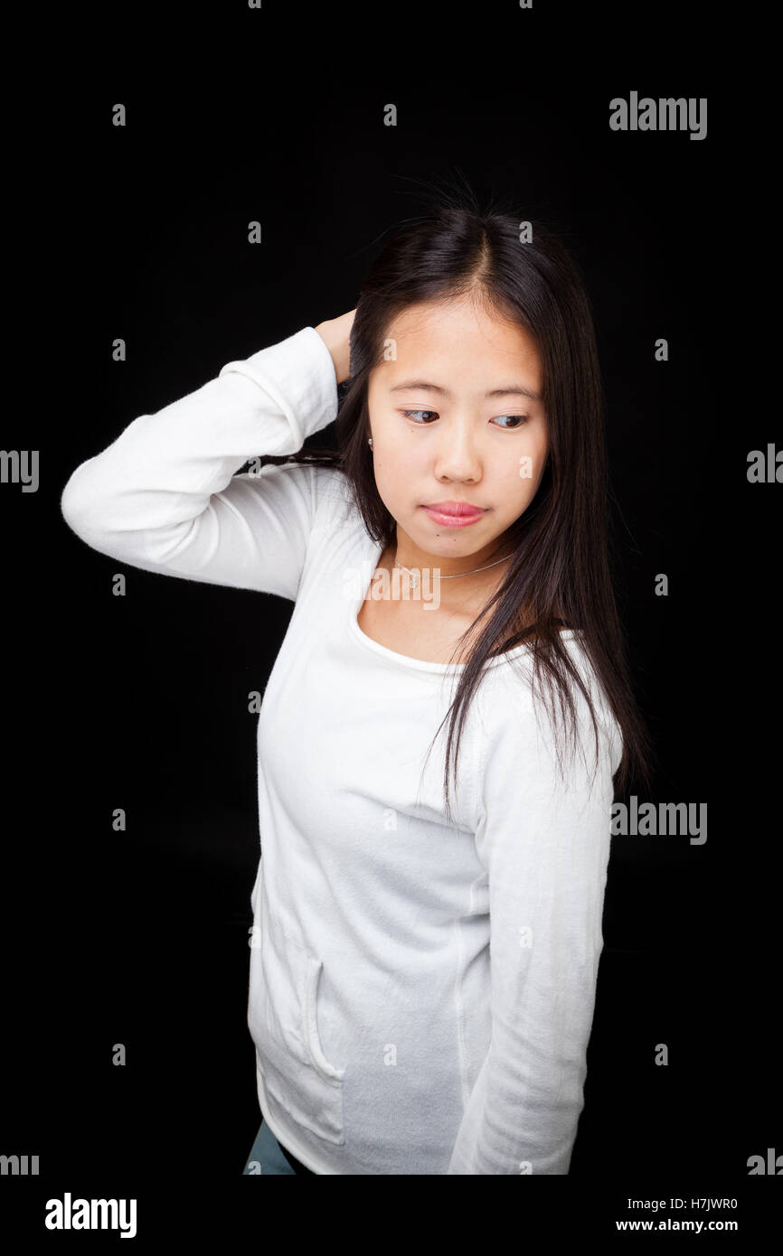Fashionable Asian teen girl striking a pose, isolated on black background Stock Photo