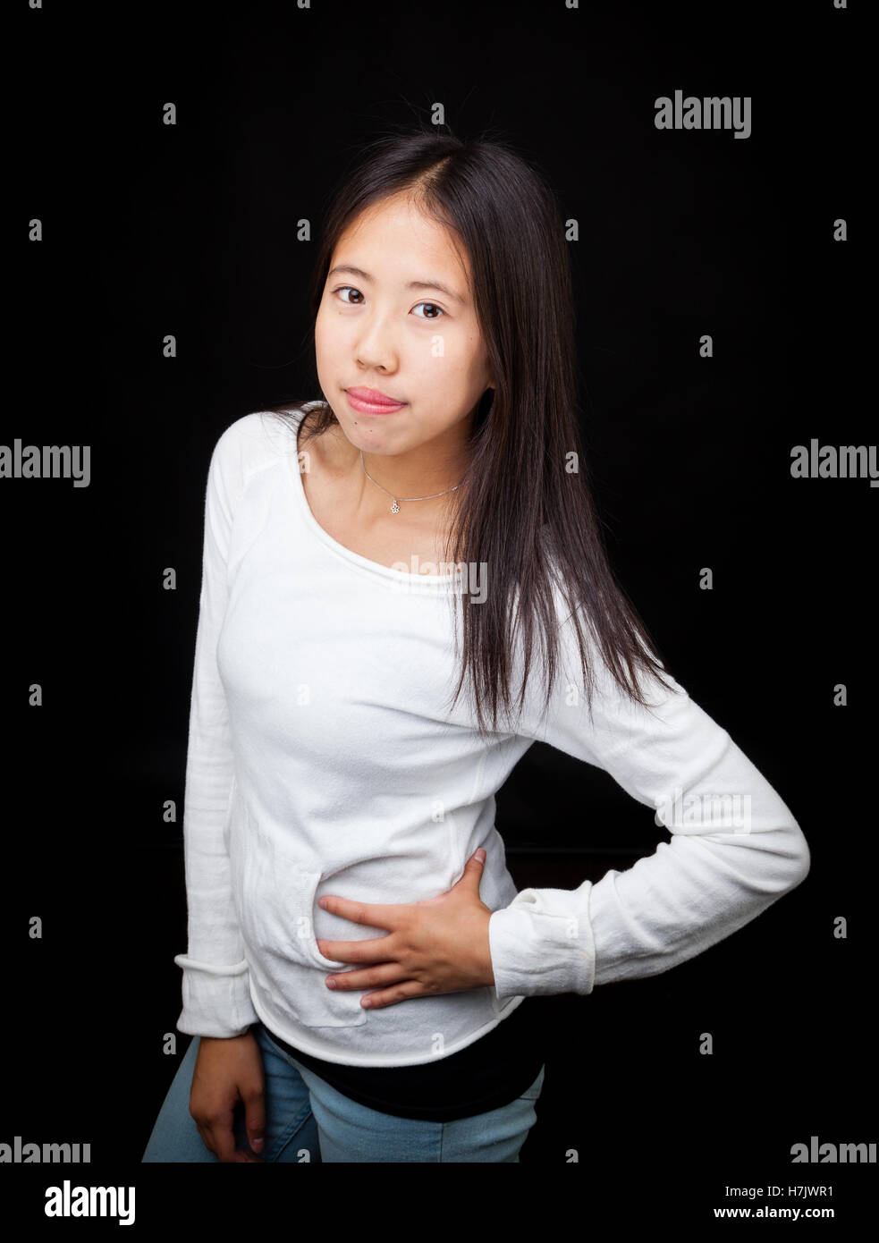 Fashionable Asian teen girl striking a pose, isolated on black background Stock Photo