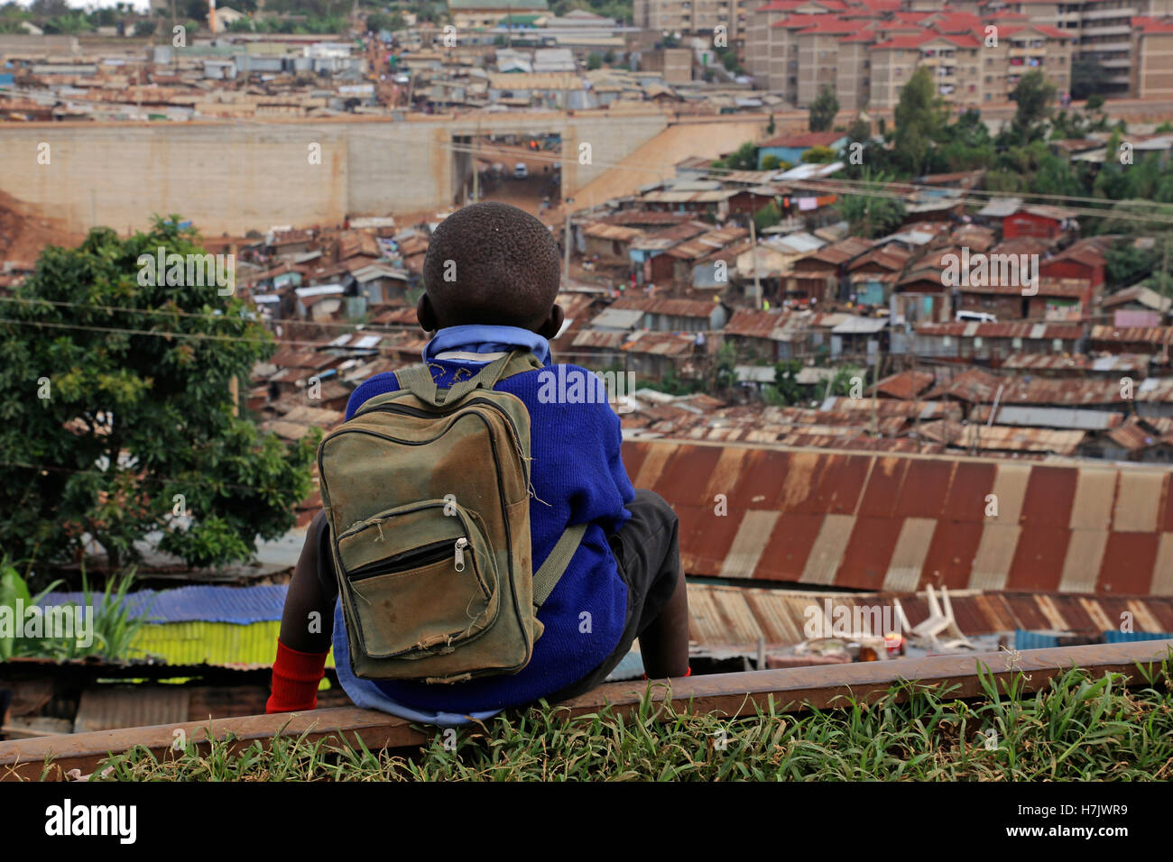 Picture was taken in Kibera Slum, Nairobi, Kenya. Boy coming back from school sat on railroad to have a look on the district. Stock Photo