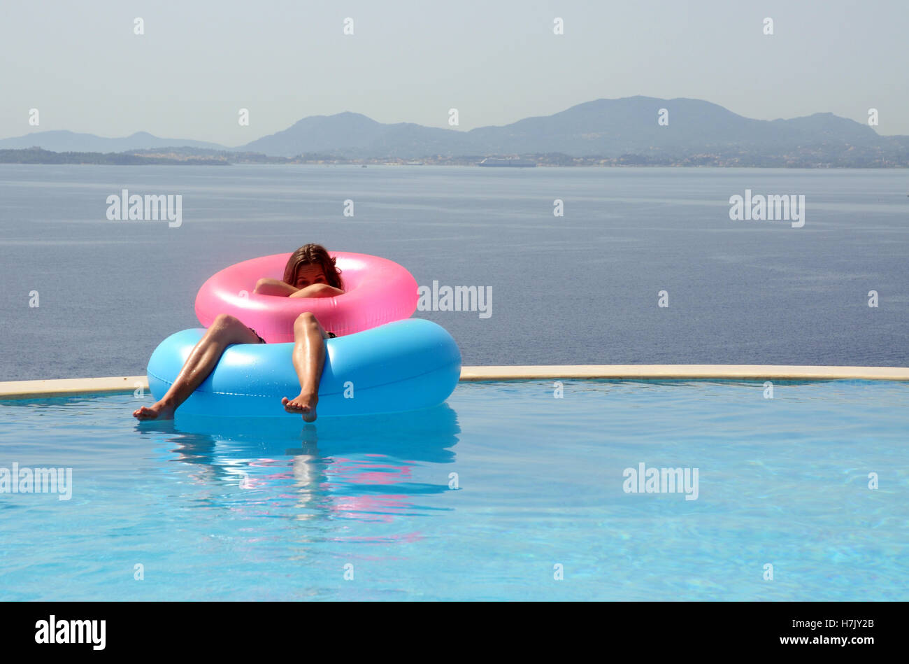 Girl in rubber rings in infinity pool Stock Photo