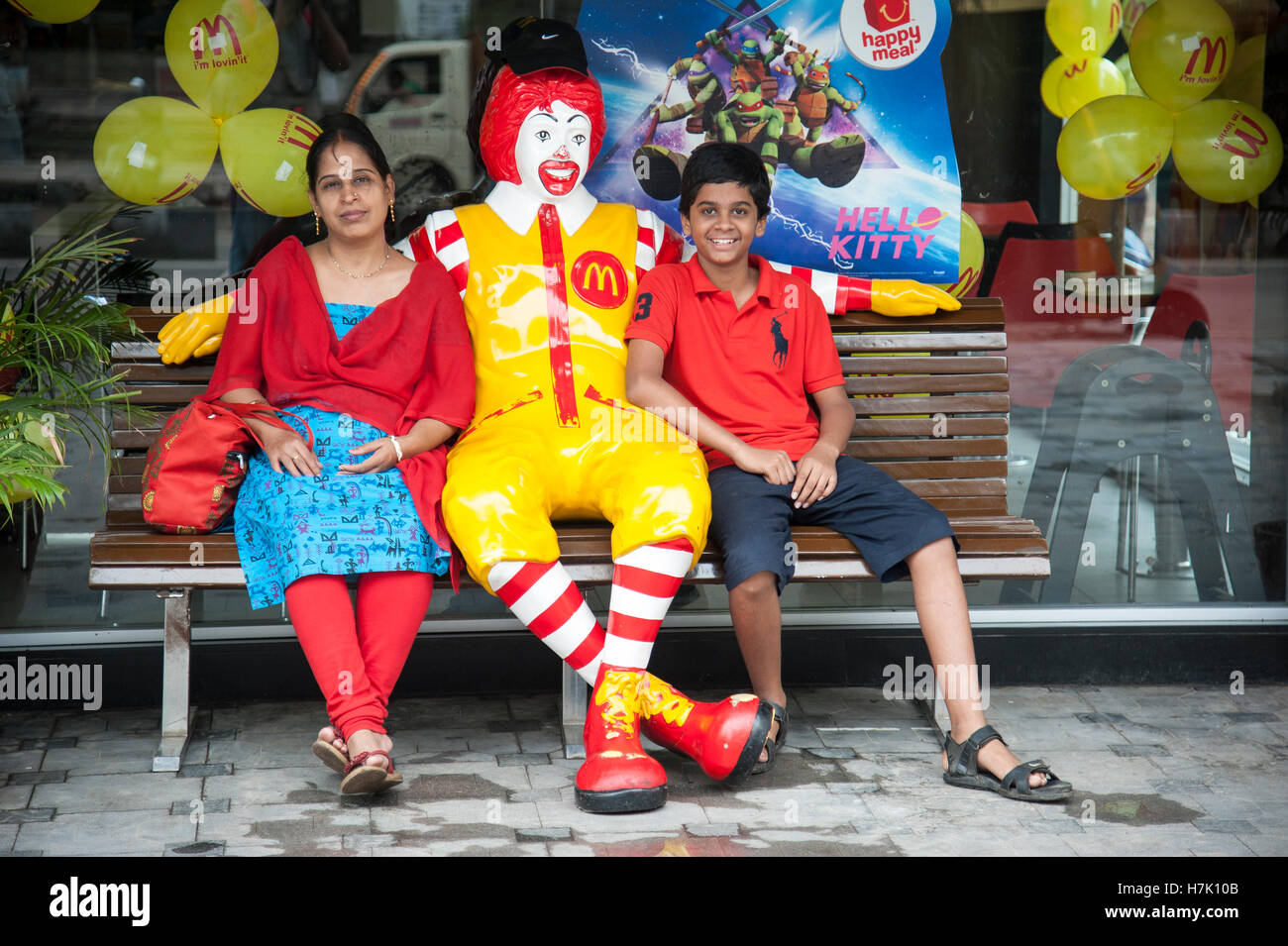 Indian Mother and Son sitting on the bench with Ronald McDonald statue in  Hyderabad Telangana india Stock Photo