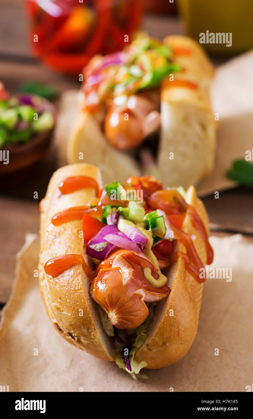Hot dog - sandwich with Mexican salsa on wooden background. Stock Photo