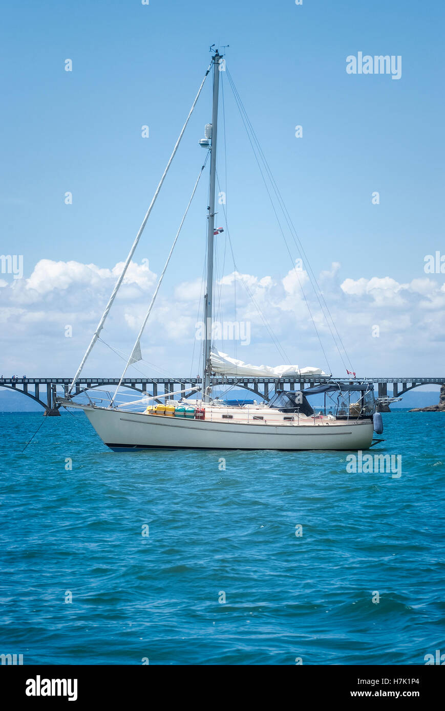 View of a sail boat ancored at Samana Bay and Los Puentes bridge at the background, Samana, Dominican Republic. Stock Photo