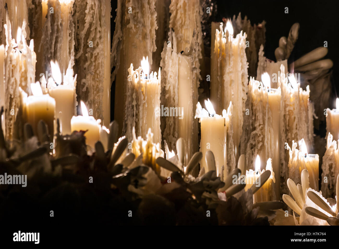 Some burning candles of wax that are melted and other candles of wax