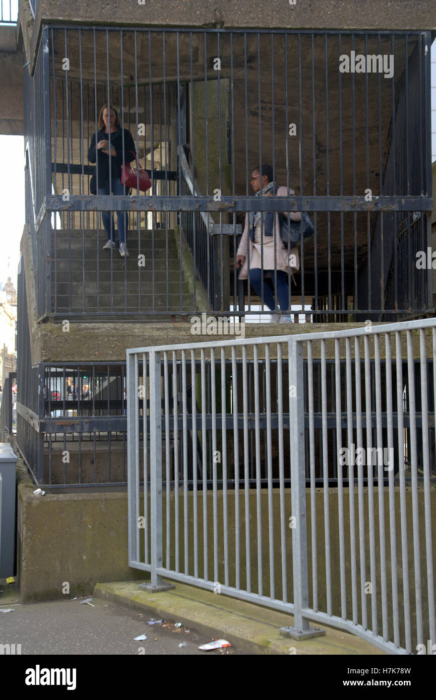 Cityscape ethnic girls caged by pedestrian steps bridge with railings om street Stock Photo