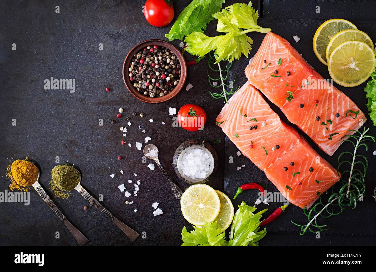 Raw salmon fillet and ingredients for cooking on a dark background in a rustic style. Top view Stock Photo