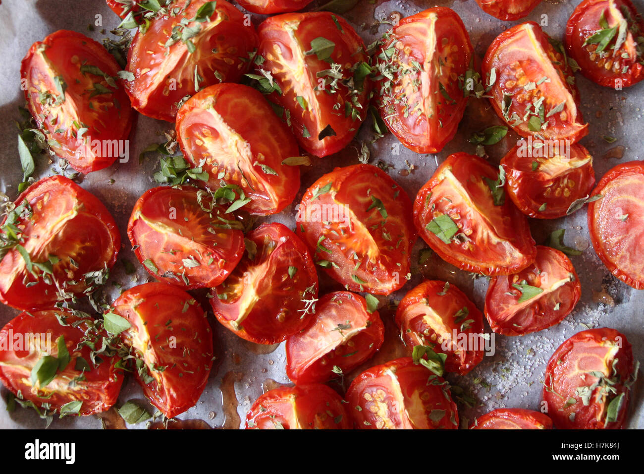 Home-made oven-roasted tomatoes, with fresh herbs and red wine vinegar on hand. Stock Photo
