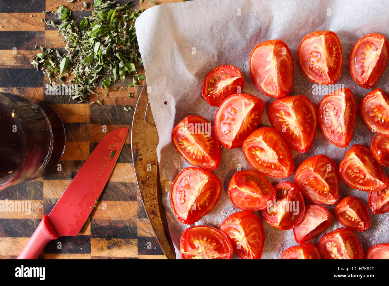 Home-made oven-roasted tomatoes, with fresh herbs and red wine vinegar on hand. Stock Photo
