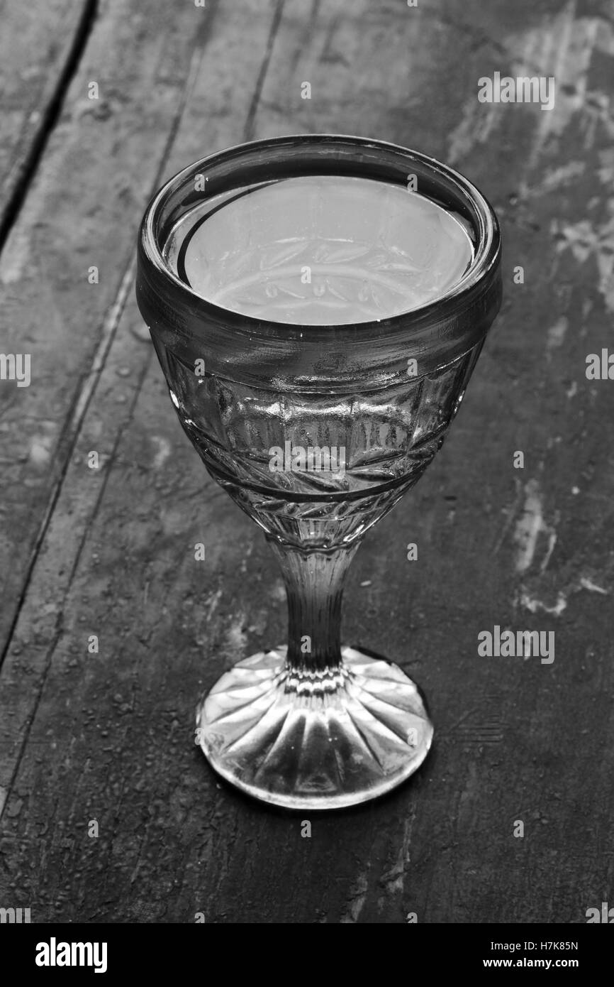 vintage shot glass with vodka on an old wooden black table closeup. black and white photo Stock Photo