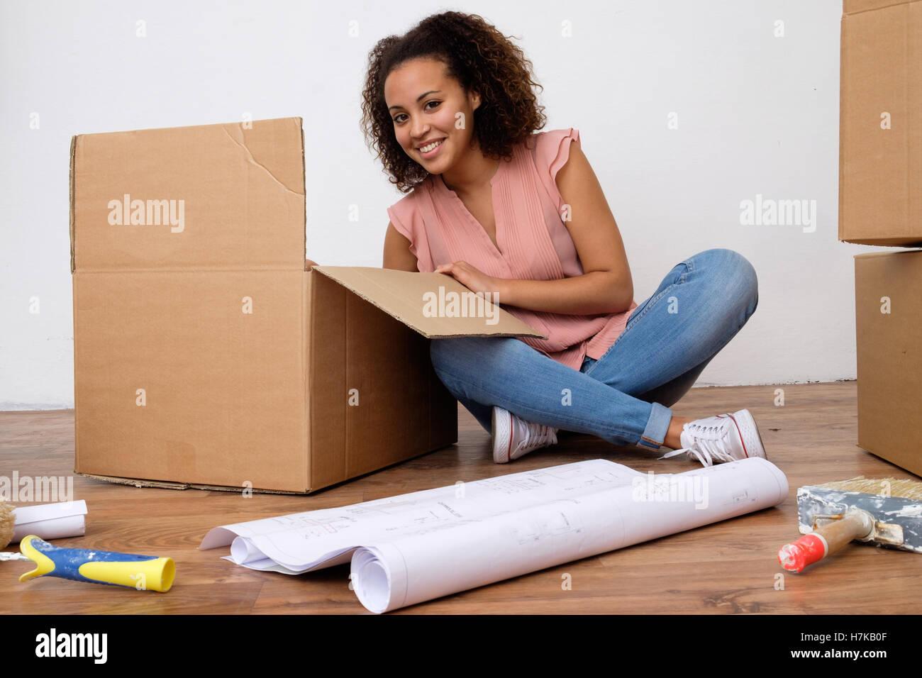 Happy woman surrounded by large boxes ready for home relocation Stock Photo