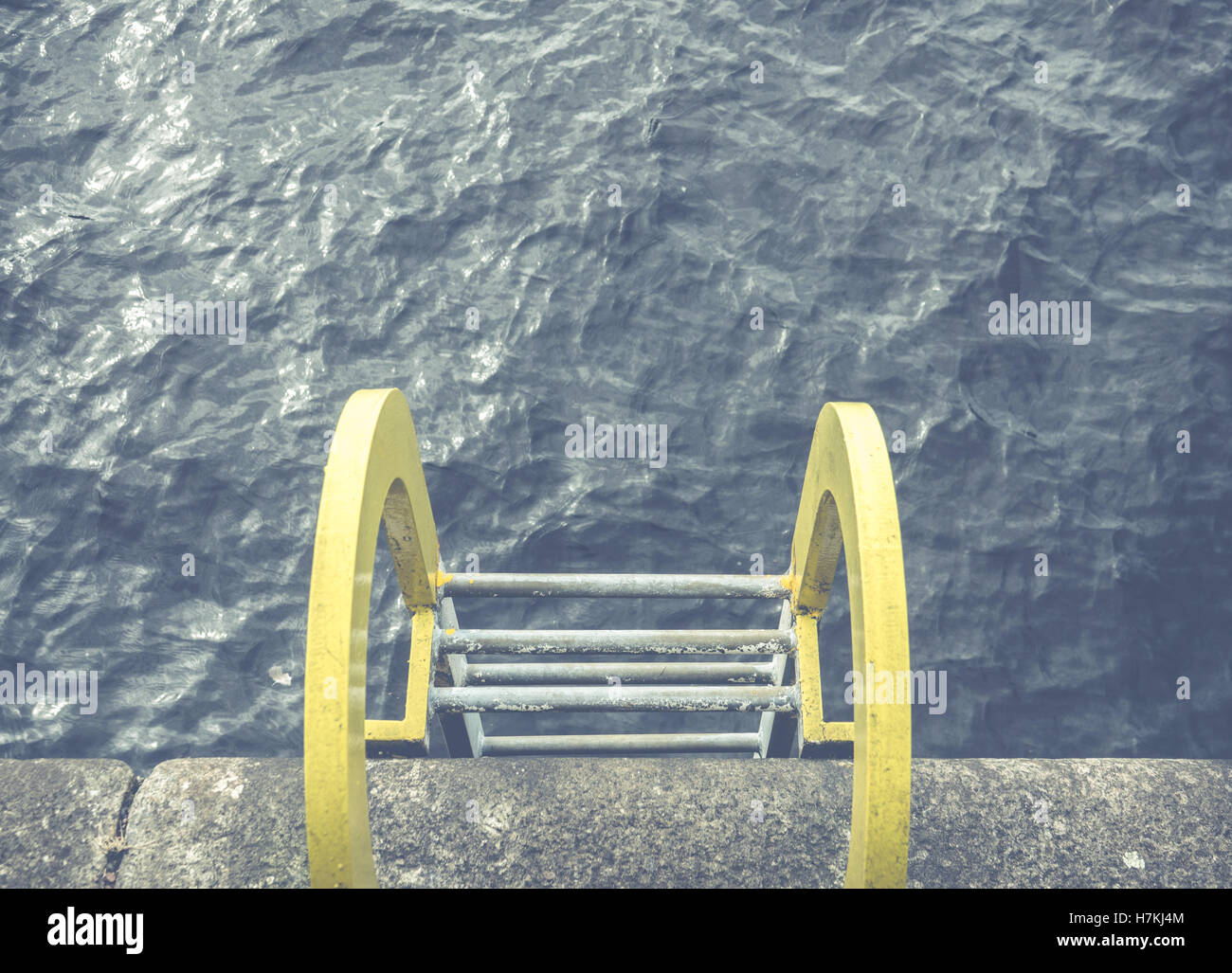 A Yellow Ladder Into Blue Ocean Water At A Harbor Stock Photo