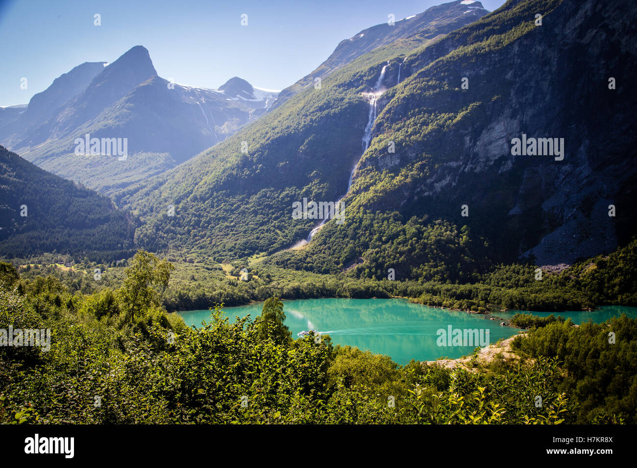 A view across Lovatnet Lake, a small boat crosses the turquoise water Stock Photo