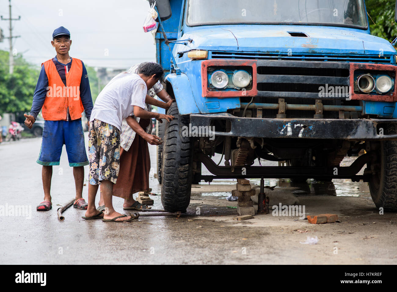 Bunch of Burmese guys fixing up a broken wheel on Manadalay street Stock Photo