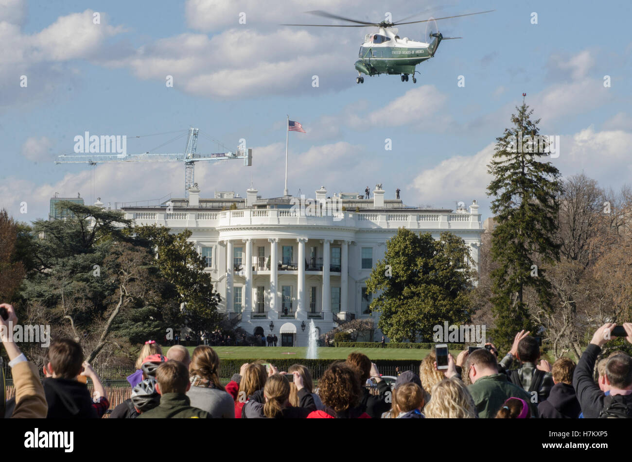 Spectators watch as Marine One helicopter prepares to land at the White House. Stock Photo