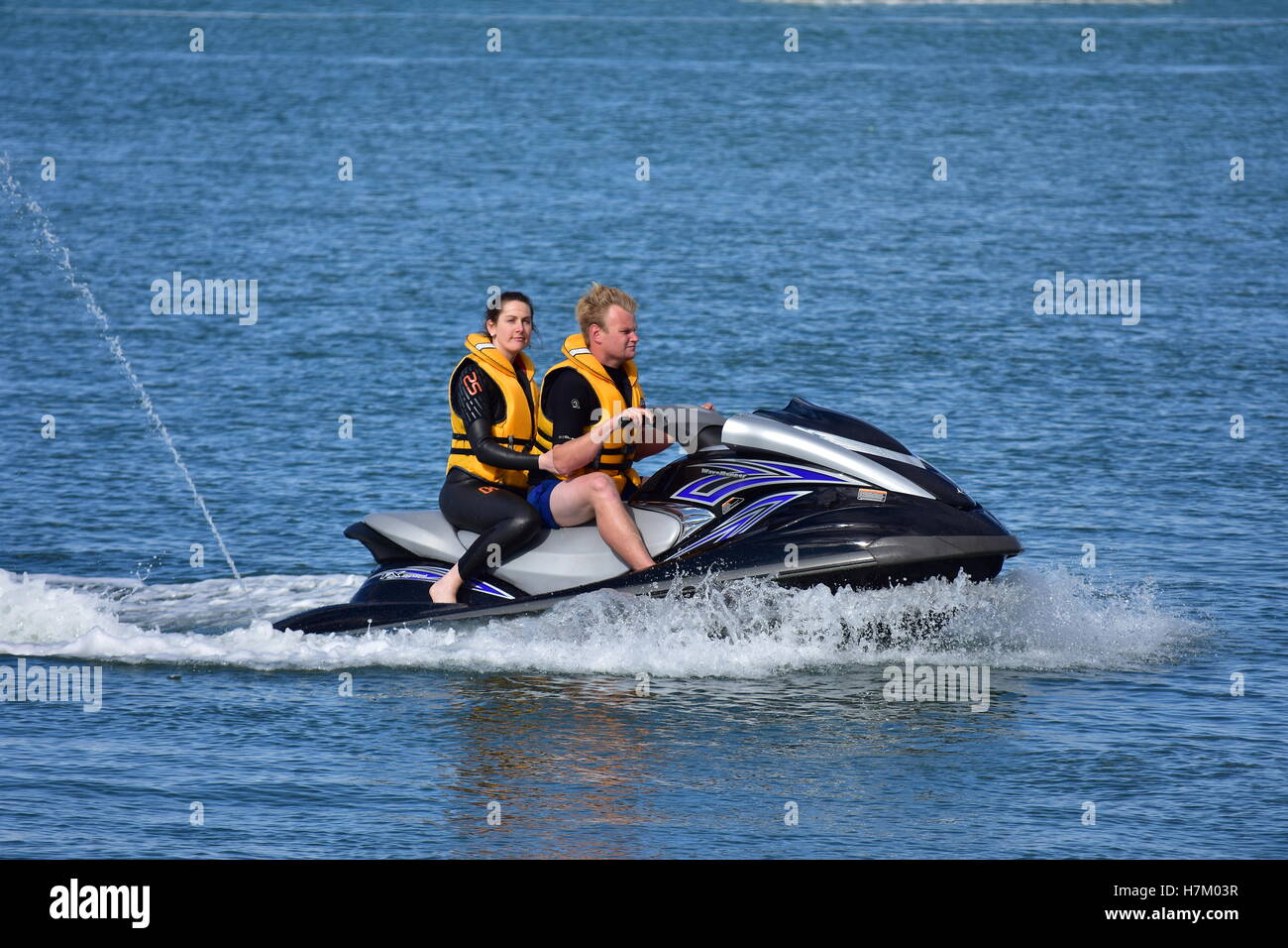 A couple in yellow lifejackets on a jetski Stock Photo