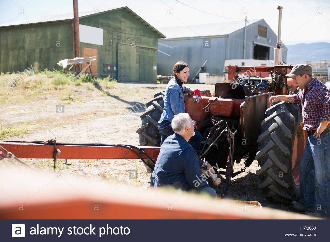 Farmers and mechanic repairing tractor on sunny farm Stock Photo Alamy
