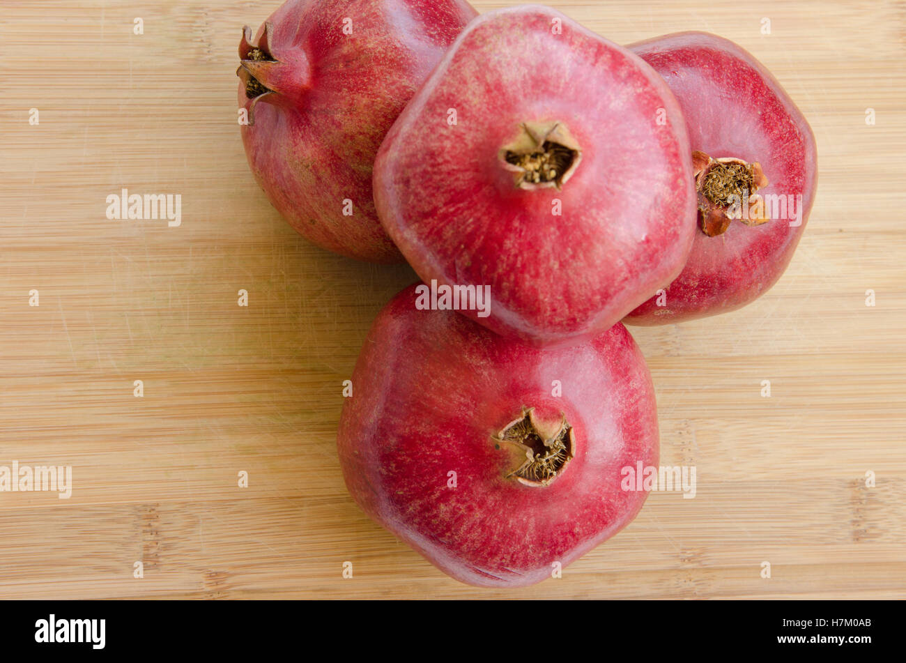 stack of pomegranate fruit on wooden cutting board Stock Photo