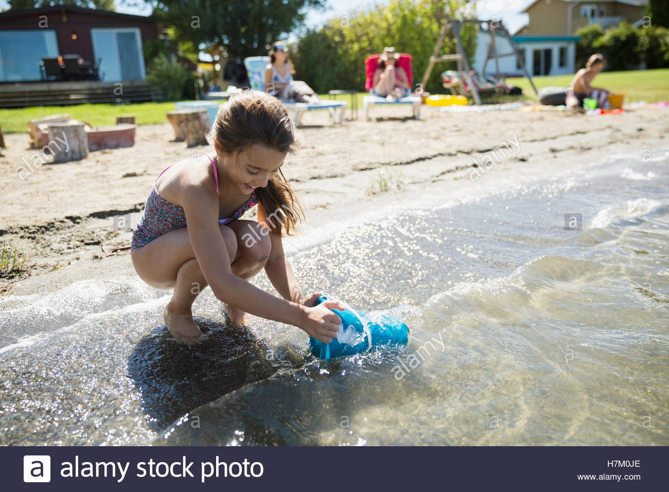 Girl filling bucket with water in sunny summer lake Stock Photo Alamy