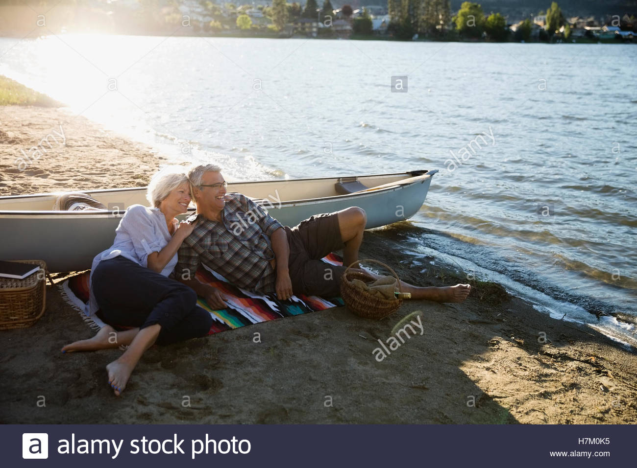 Affectionate retired couple relaxing on sunny summer lake beach Stock Photo