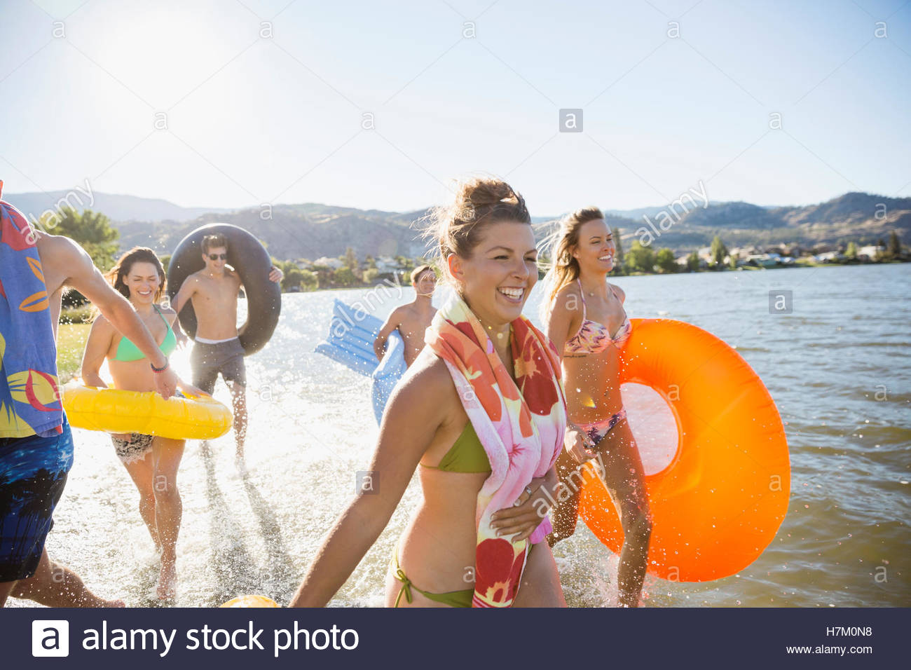 Young friends running in sunny summer lake Stock Photo
