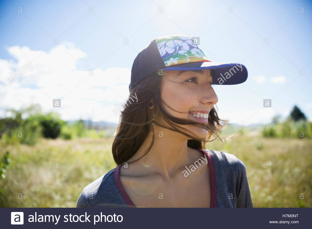 Smiling teenage girl wearing baseball cap in rural sunny summer field