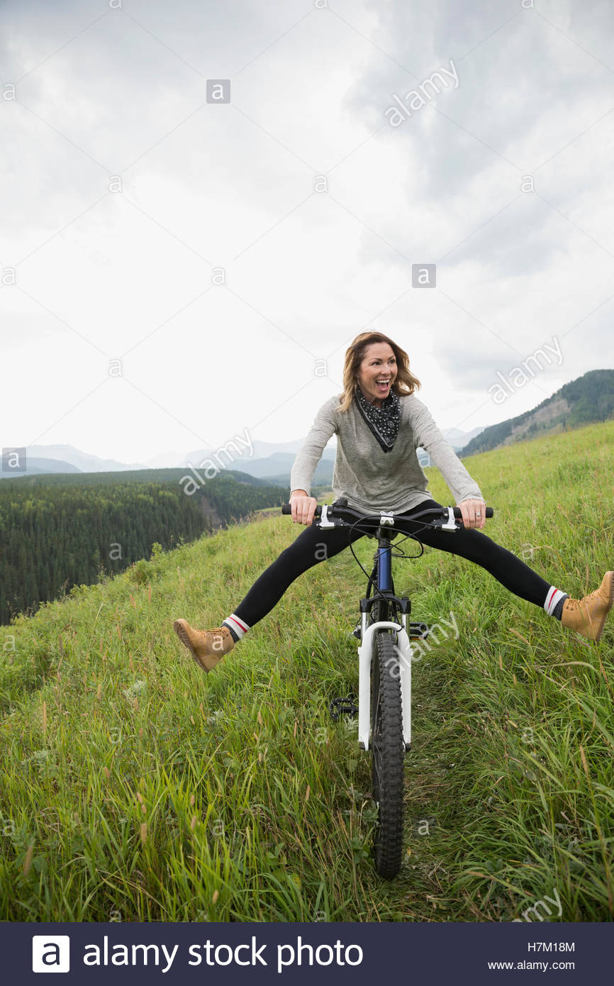 Playful woman riding mountain bike in remote rural field Stock Photo Alamy