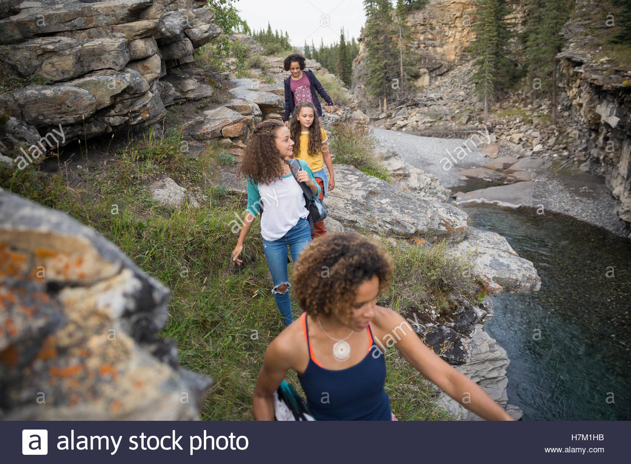 Mother and daughters hiking over rocks above water Stock Photo