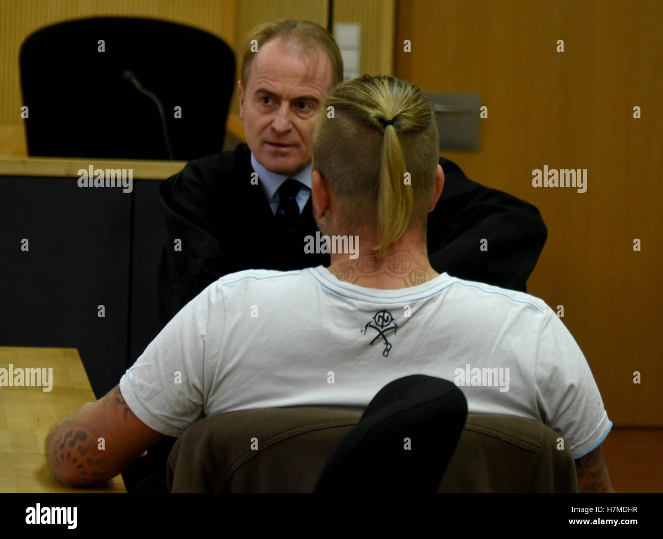 Neuruppin, Germany. 07th Nov, 2016. The NPD local politician, Marcel Z, is waiting for the beginning of the appeal case with his lawyer Wolfram Nahrath (behind) on 07 November 2016 in Neuruppin, Germany, 07 November 2016. The accused is said to have caused incitment of the masses by displaying a back tattoo in a swimming pool with outline of a concentration camp and the Nazi-utilised slogan 'Jedem das Seine' (lt. To Each His Own). In 2015 he was sentenced to a provisional sentence because due to incitement. The prosecutors and defense have appealed. Photo: BERND SETTNICK/DPA/Alamy Live News Stock Photo