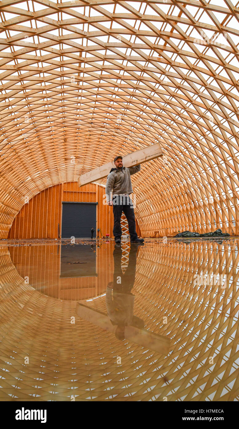 Carpenter Master Eric Bensemann of the company Elite Holzbau standing in his carcass of a production hall made of spruce wood in the industrial park in Herzfelde, Germany, 7 November 2016. The ceiling construction reflects in a giant puddle created by the last night's rain. The new company headquarters of Elite Holzbau are currently constructed using the so-called Zollinger architecture. Diamond-shaped wooden elements are connected in order to form a carrying construction. The building measures 11 meters in hight, 51 meters in length and 24 meters in width. 60 tons of spruce wood were used. PH Stock Photo