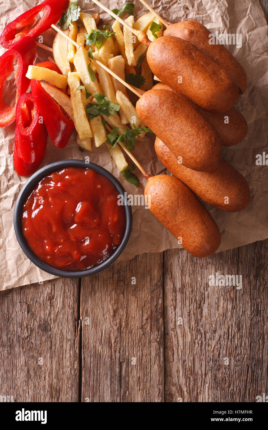 Corn dogs, french fries, pepper and ketchup on the table. vertical view from above Stock Photo