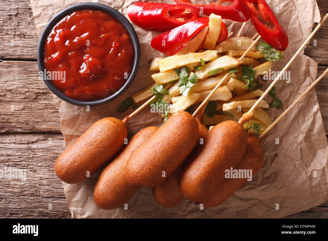 Corn dogs, french fries, pepper and ketchup on the table close-up. Horizontal view from above Stock Photo