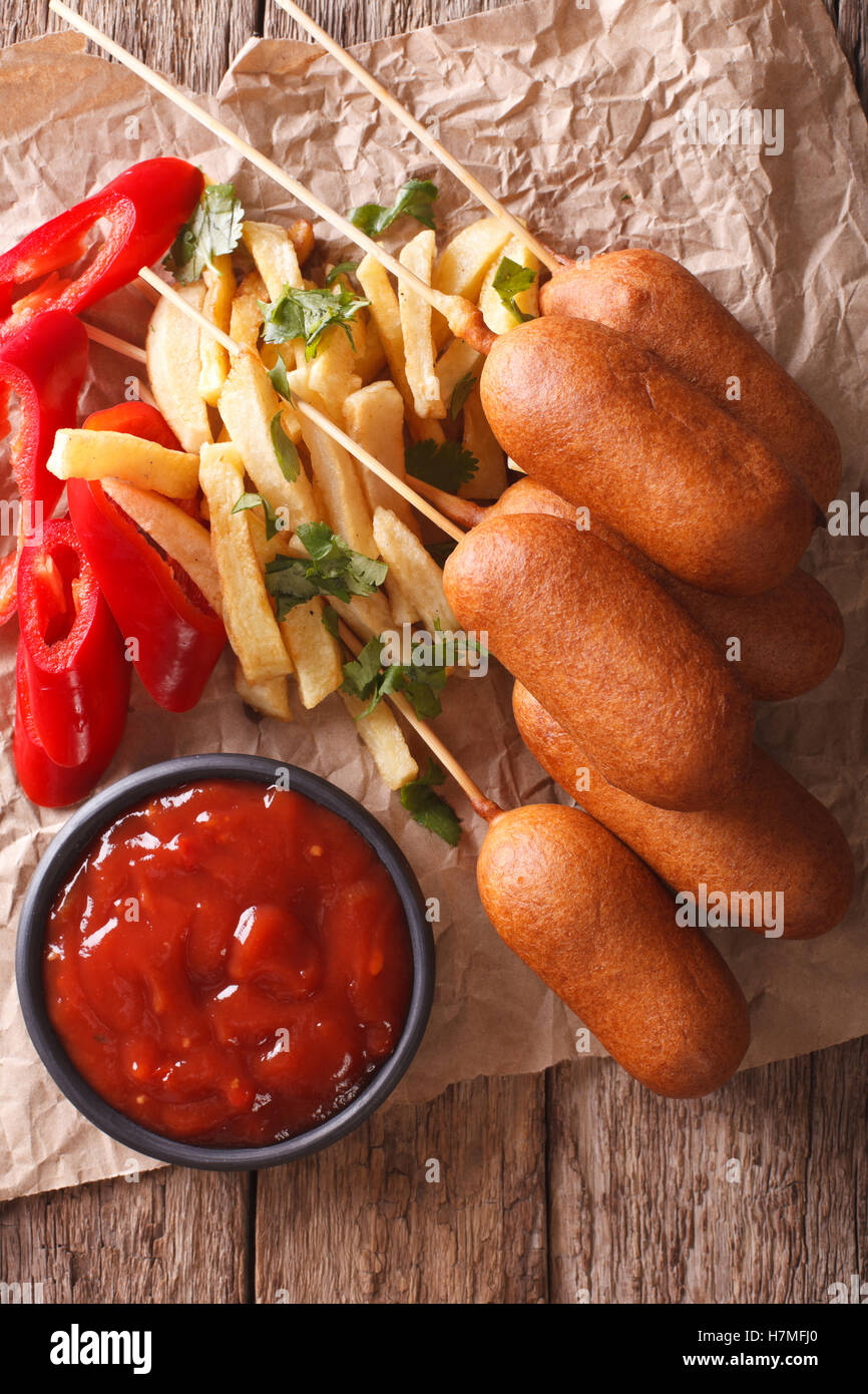 Corn dogs, french fries, pepper and ketchup on the table close-up. vertical view from above Stock Photo