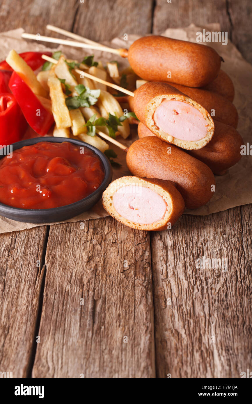 Corn dogs, french fries and ketchup on the table. vertical, rustic Stock Photo