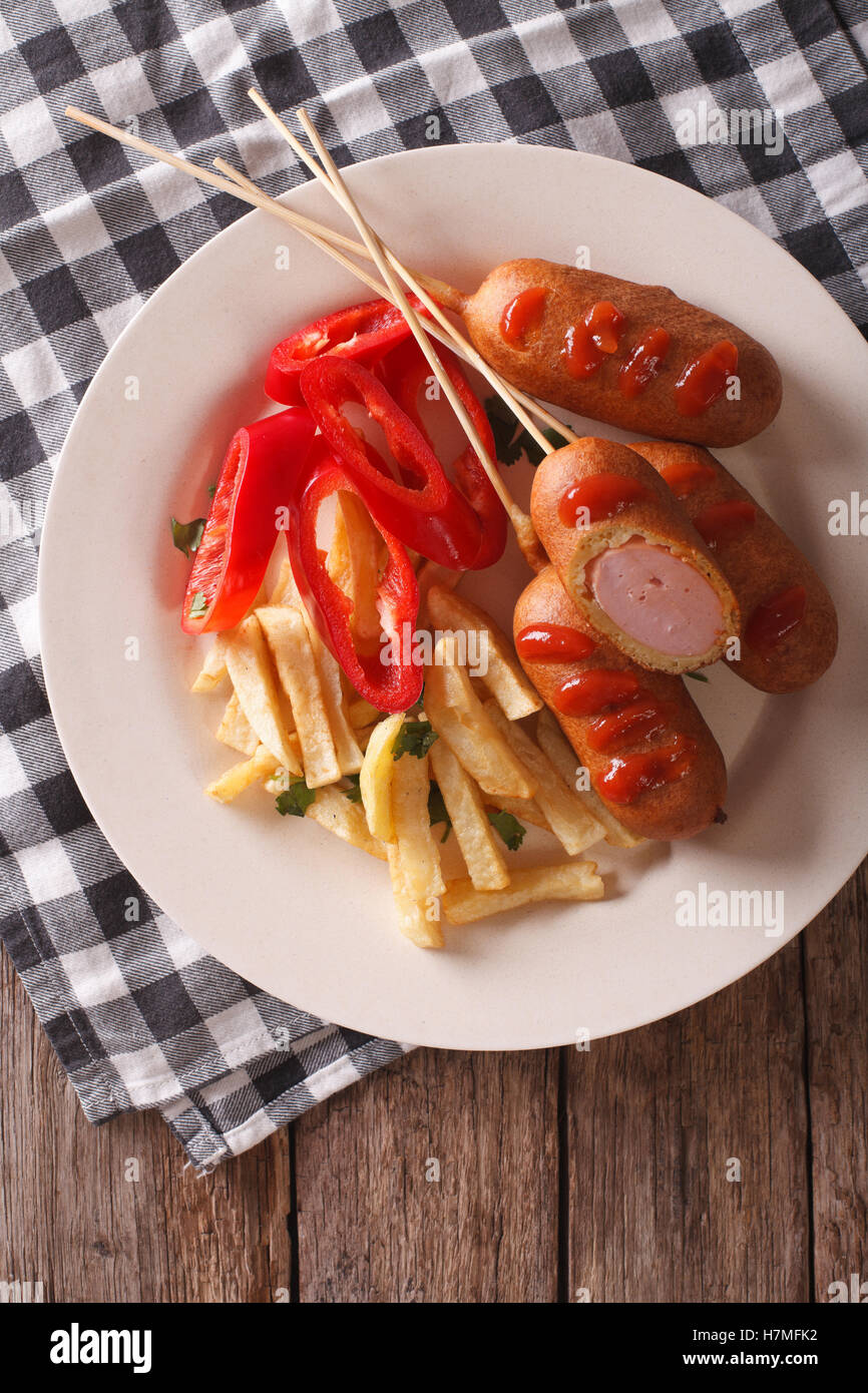 Fast food: corn dog and fries on a plate close-up on the table. vertical view from above Stock Photo