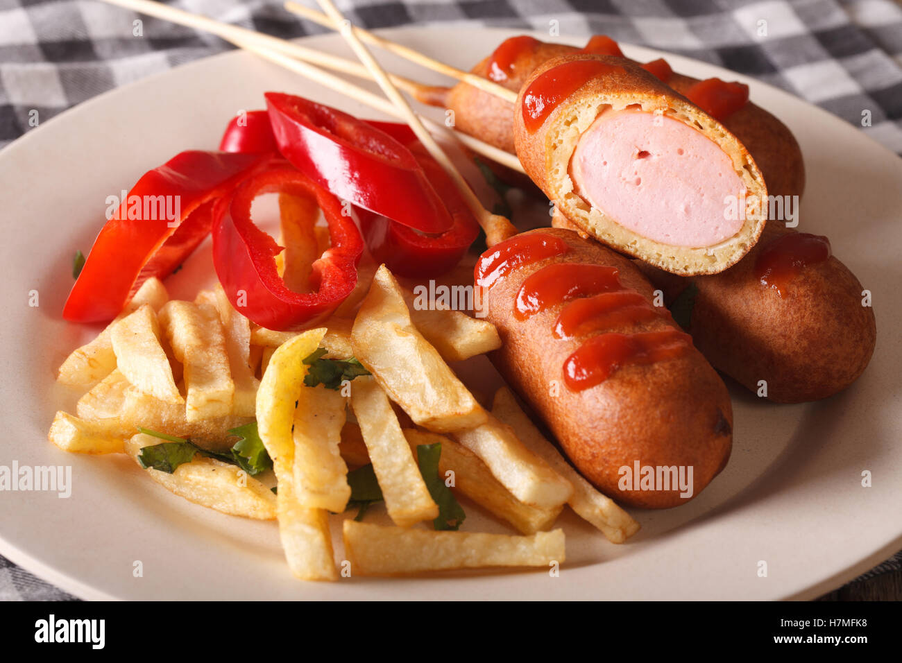 Corn dog with fries and vegetables on a plate close-up on the table. Horizontal Stock Photo