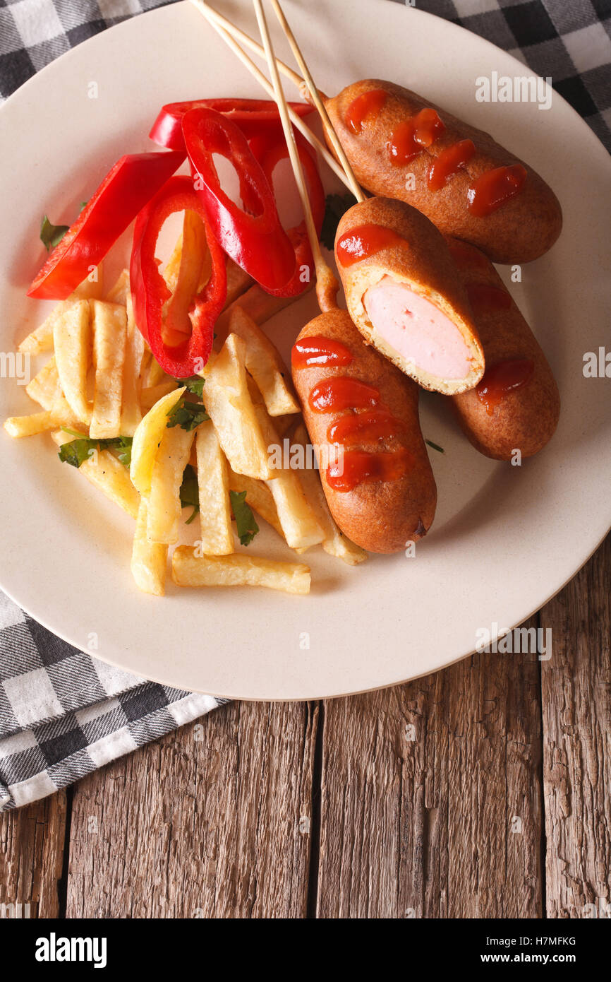 Corn dog with fries on a plate close-up on the table. vertical view from above Stock Photo