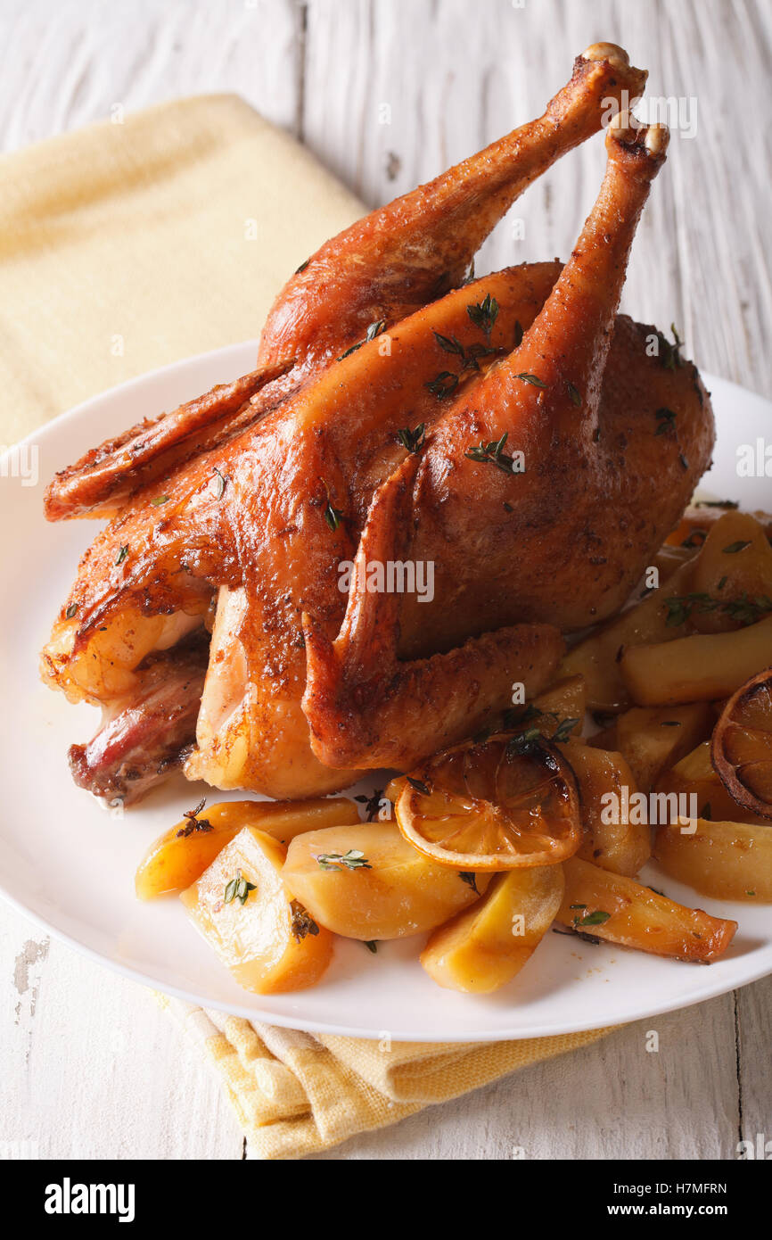 Whole baked chicken with lemon and thyme close-up on a plate on the table. vertical Stock Photo
