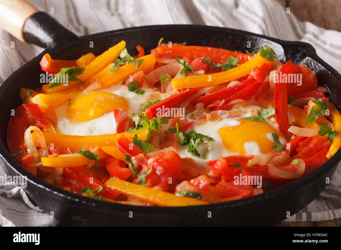 A delicious breakfast fried eggs with peppers in a pan closeup