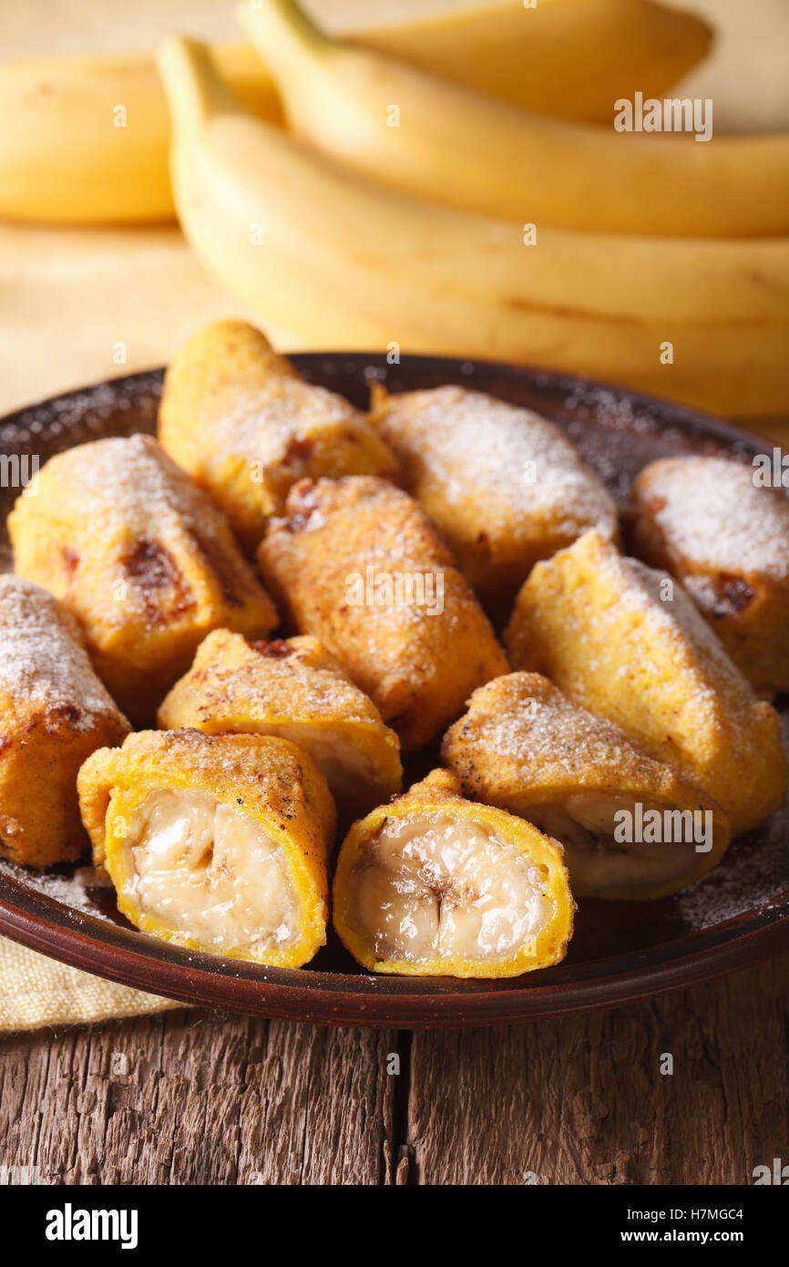 Fried bananas in batter sprinkled with powdered sugar closeup on a