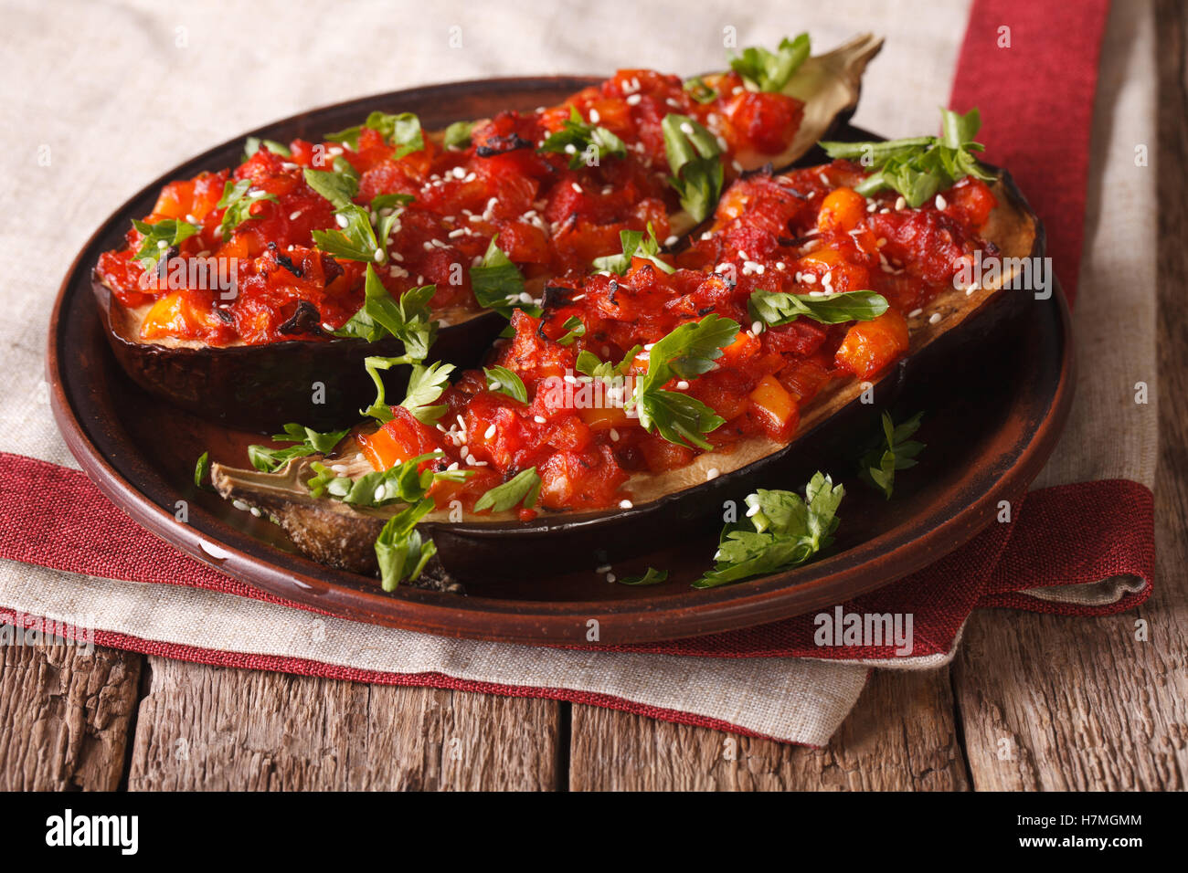 Turkish halves of baked eggplant stuffed with vegetables close-up on a plate. horizontal Stock Photo