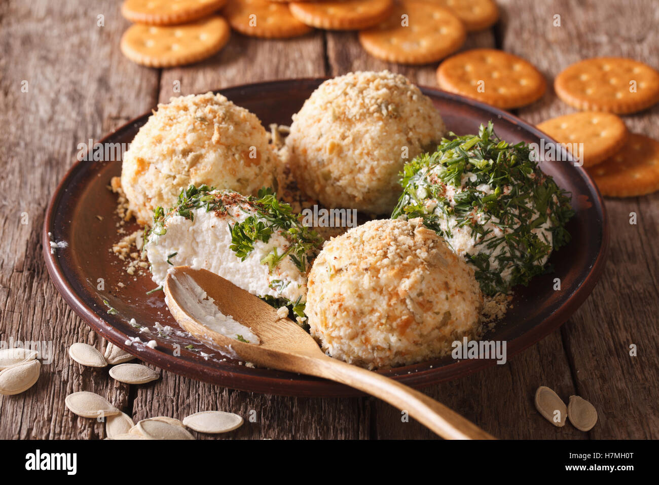 Cottage cheese balls with crackers, herbs and pumpkin seeds close-up on a plate. Horizontal Stock Photo