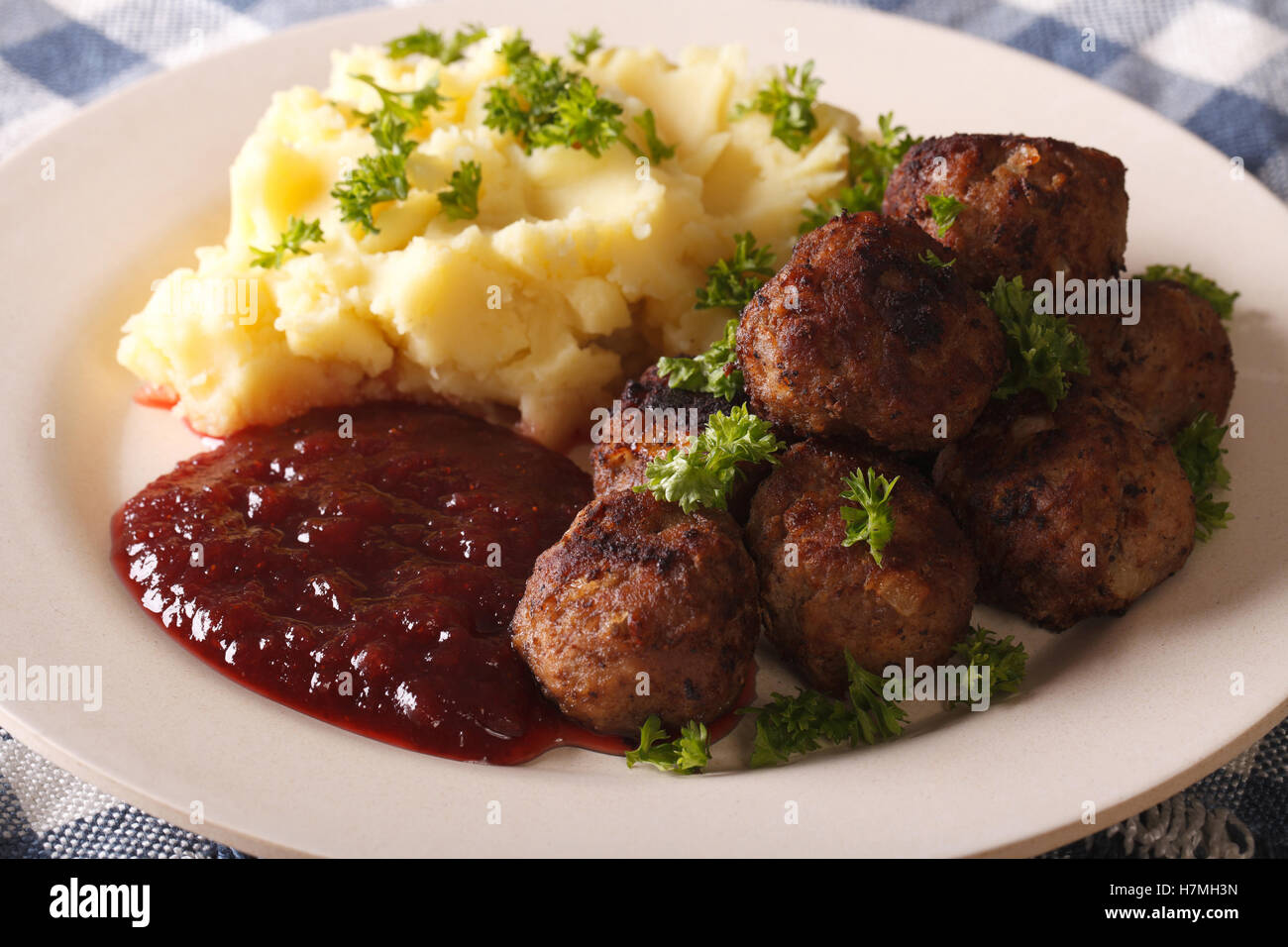 fried meatballs, lingonberry sauce with potato garnish on a plate close