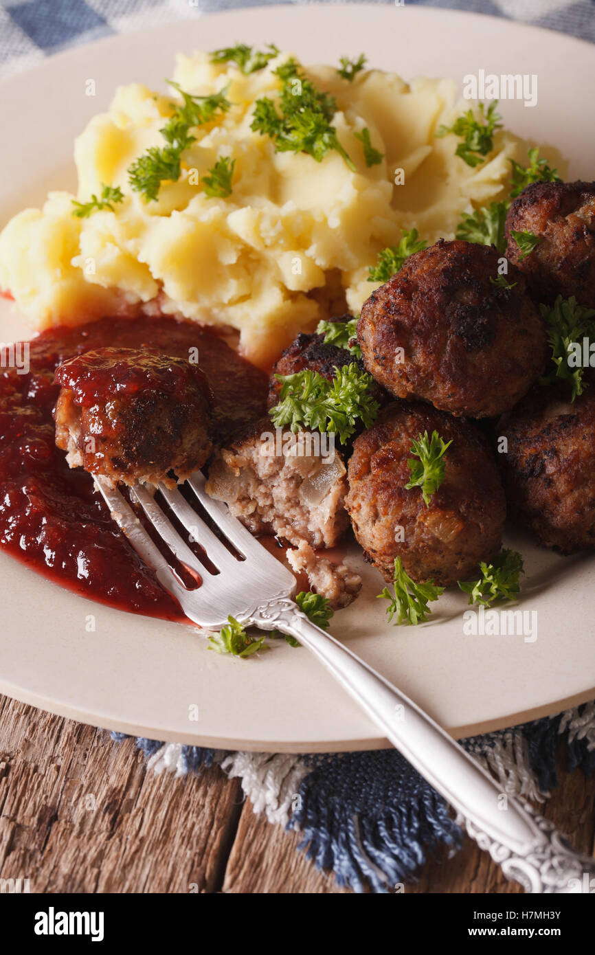 Swedish food: meatballs kottbullar, lingonberry sauce and mashed potatoes on a plate macro. Vertical Stock Photo