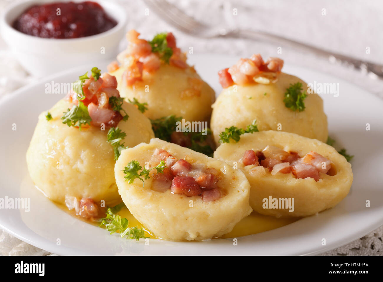 Potato dumplings with bacon, onion and ham close-up on a plate and berry sauce. horizontal Stock Photo